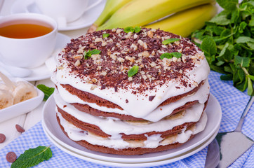Chocolate cake with cream and bananas. Rustic style