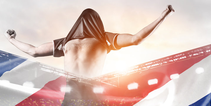 Costa Rica national team. Double exposure photo of stadium and soccer or football player celebrating goal with his jersey on head