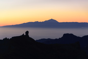Silhouettes of the mountains of the islands of Gran Canaria and Tenerife. Both islands separated by a sea of ​​clouds. and a sunset.