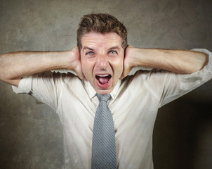 young crazy and desperate messy business man on necktie screaming stressed and frustrated with hands on ears in stress expression overwhelmed