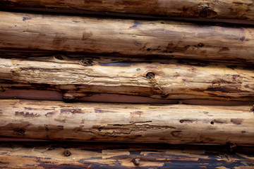 Wooden logs are arranged side by side to create a ceiling surface texture and brown. The picture is horizontal.