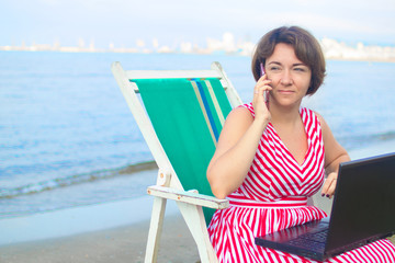 Young woman using laptop computer on a beach. Freelance work concept