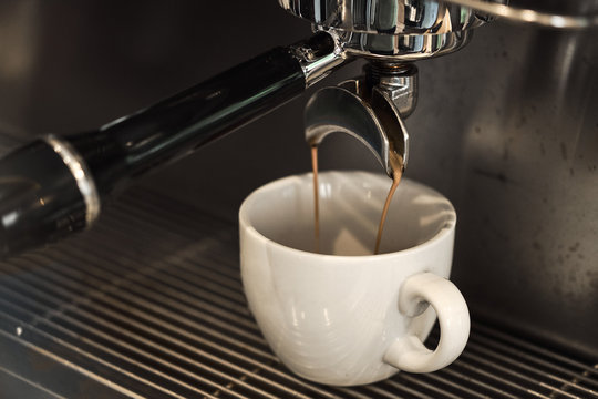 Coffee being poured to cup with professional machine