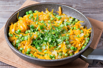 Peas, onions and carrots on a frying pan