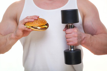 Fat man with a hamburger holds dumbbells isolated on white. The concept of choosing between harmful food and a healthy lifestyle. Portrait of overweight person who spoiled healthy meal . Junk meal