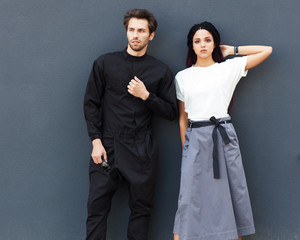 Beautiful young couple posing in a summer cool outfit. Youth street fashion. Overalls, T-shirt, long skirt.