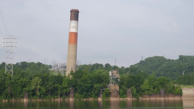 An implosion of a factory's old smoke stack on the banks of the Ohio River. Pittsburgh suburbs. Shot at 60fps for optional slow motion use. Audio included.  	