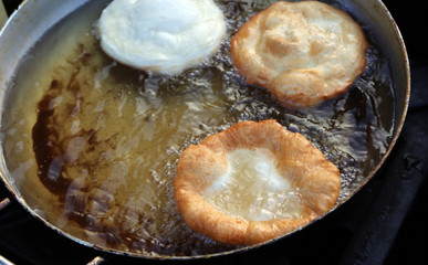 three pancakes cooked in the boiling oil of a large pot