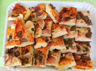 slices of pizza stuffed with ham and mushrooms on a white tray