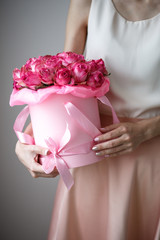 Close-up photo of gorgeous bouquet of pink roses in a hat box. Woman hands with manicure, nail polish art