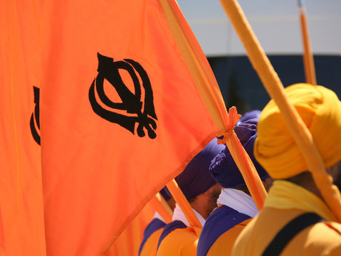 orange flag with symbol of the Sikh religion called KHANDA forme