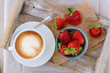 Fresh strawberries and a cup of coffee in a wooden tray. Top view. Selective focus.