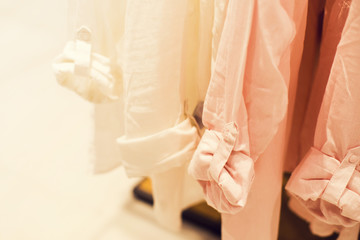 Women's shirts of pastel tones on a hanger in shop, selective focus