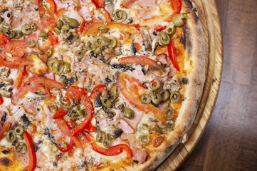 Tasty pizza with chicken meat, ham, mushrooms, tomatoes and olives