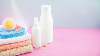 Obraz na płótnie Canvas bathroom accessories - towels and shampoos,bath foam, cream on a light, bright blue and pink background The concept of caring for yourself, your body. Place for copy space Banner concept