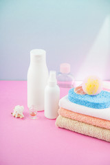bathroom accessories - towels and shampoos,bath foam, cream on a light, bright blue and pink background The concept of caring for yourself, your body. Place for copy space