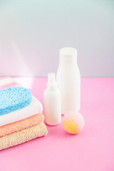 Fototapeta na wymiar bathroom accessories - towels and shampoos,bath foam, cream on a light, bright blue and pink background The concept of caring for yourself, your body. Place for copy space
