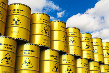 Group of stacked yellow drums with radioactive waste against blue sky