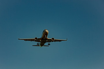 Passenger plane flying in the blue sky in sunlight rays