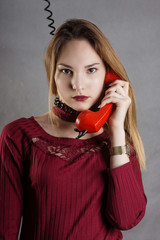 Young girl talking on the phone with a wound around the neck telephone cord