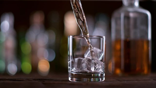 Pouring whisky from the bottle at vintage bar in super slow motion. Shot with high speed cinema camera Phantom VEO 4K , 1000fps.