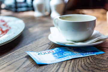 New Russian banknotes denominated in 2000 rubles for payment the bill in a restaurant on a wooden table under a white cup