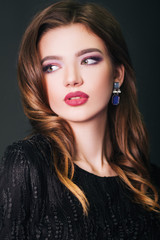 Fototapeta premium Beautiful girl in a black dress. model with make-up. Studio portrait