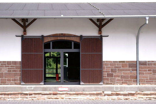 Holzschiebetür Güterbahnhof / Das Fachwerkgebäude eines Güterbahnhofes mit einer Holzschiebetür sowie einer Rampe.