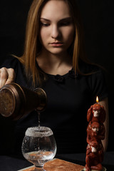 Young girl preparing hot cocktail of gin in the dark by candlelight