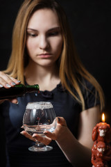Young girl preparing hot cocktail of gin in the dark by candlelight