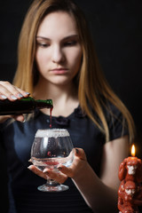Young girl preparing hot cocktail of gin in the dark by candlelight