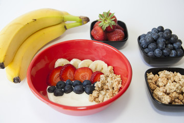A healthy breakfast bowl of banana, blueberry and strawberry with granola on Greek yogurt.
