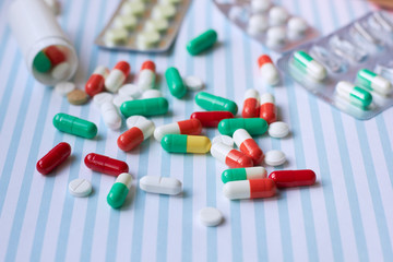 Colored tablets and capsules are scattered on the table.