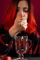 A young girl with red hair is preparing mulled wine. Red and black palette