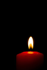 Lit red candle on a black background