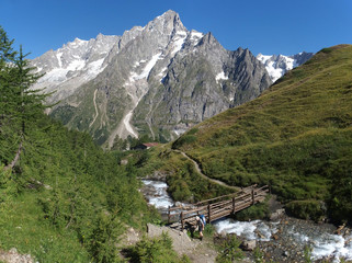 Fototapeta na wymiar Alpy, Włochy, Tour du Mont Blanc - wzdłuż masywu Mont de la Saxe, widok z mostem nad rzeką