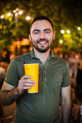 Handsome man drinking coctail or beer at street park night evening party