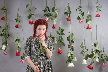 Girl with red hair among hanging roses