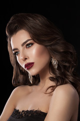 Fototapeta premium Fashion glamorous portrait of a girl on a dark background. Elegant hairstyle, bright makeup and lip color. Hollywood picture.