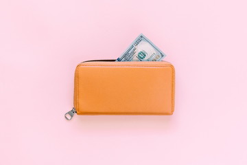 Purse with hundred dollar banknotes on pink background. Flat lay, top view, copy space 