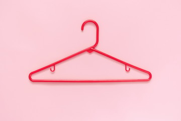 Red plastic plastic clothes-hanger on a pink background. Flat lay, top view, copy space