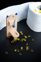 Wooden toy toilet, capsules and paper on black background