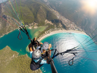 Paragliding in the sky. Paraglider tandem flying over the sea with blue water and mountains in...