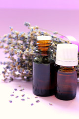 Essential oil and lavender flowers close up on purple background. Aromatherapy