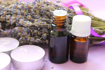 Essential oil and lavender flowers close up on purple background. Aromatherapy