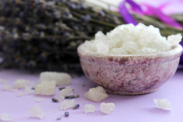 Obraz na płótnie Canvas Large crystals of sea salt and lavender flowers, close-up on a purple background. Aromatherapy and Spa treatments, bathing, relaxation