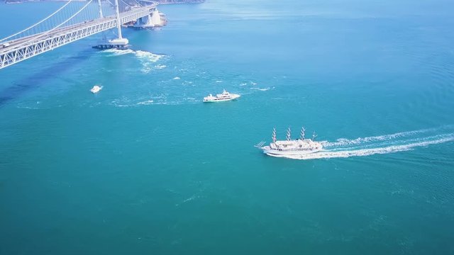 Naruto bridge, whirlpool viewing boats travel below ferrying tourists in Tokushima Japan.