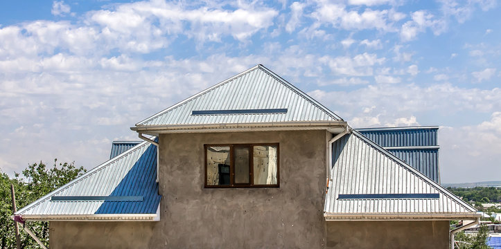The roof of the house is made of galvanized metal profile against the sky