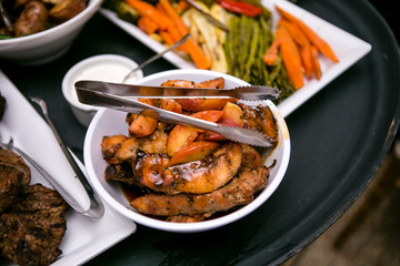 Detail of dinner food including fish, fruit, and vegetables being held by a banquet server