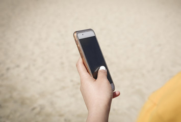 Close-up of a woman holding a smartphone at the beach